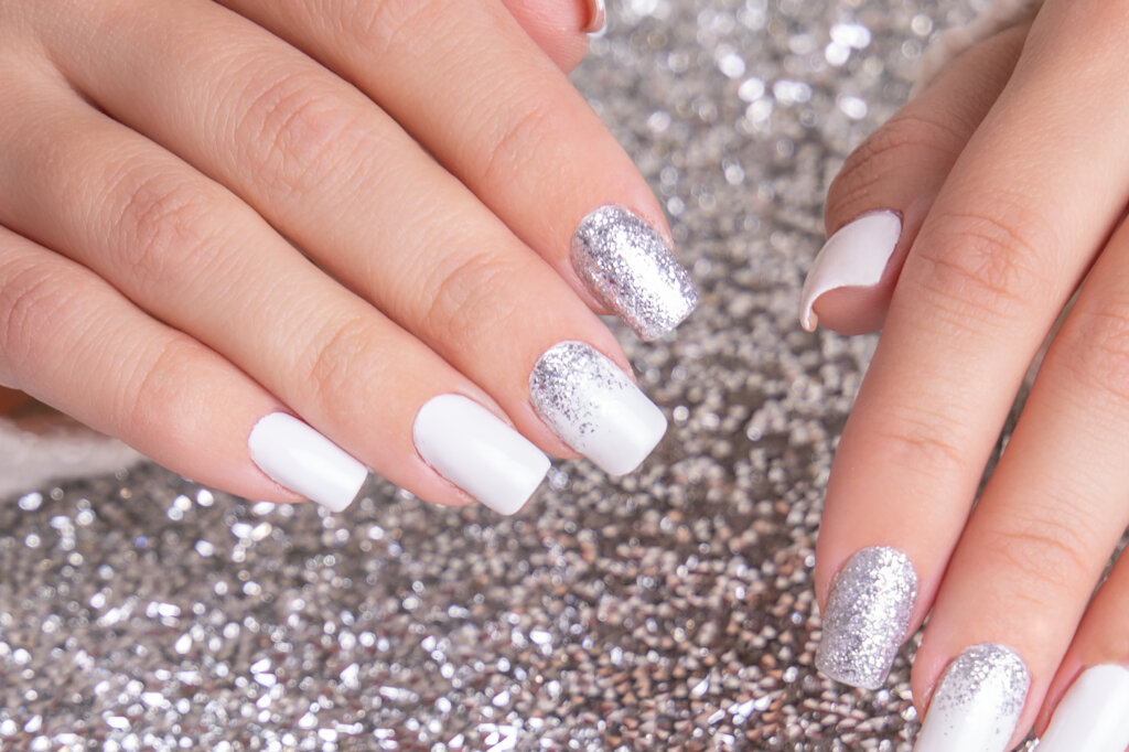 beautiful-female-hands-with-romantic-manicure-nails-white-gel-polish-with-silver-glitter